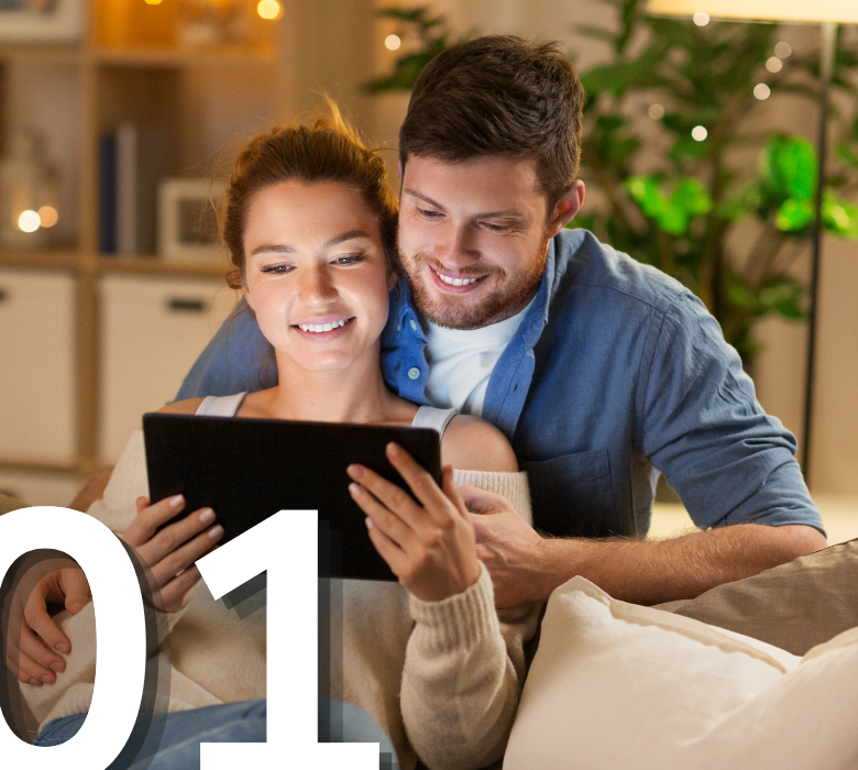 A couple sitting together at home browsing paint colors on a tablet for a home improvement project