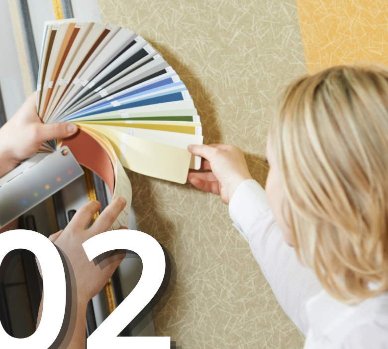 A store employee showing a customer paint swatches from a fan deck to color match a wallpaper pattern